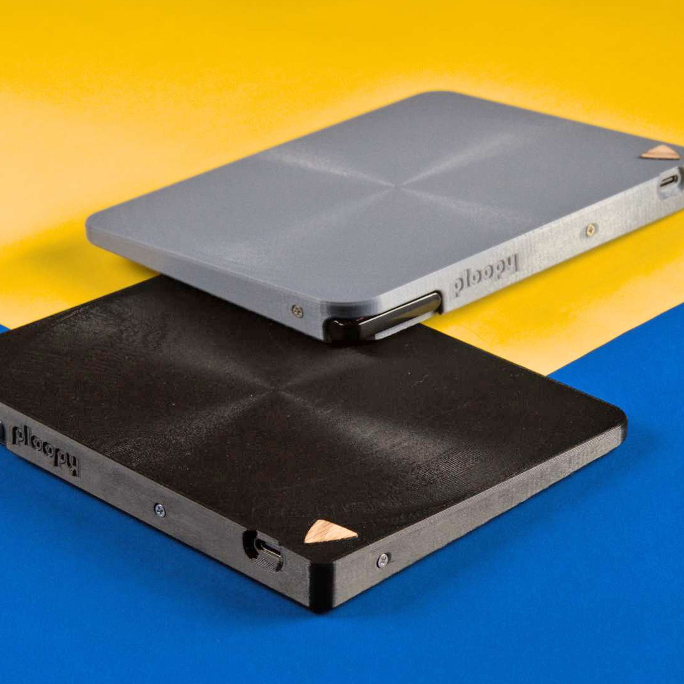 Ploopy’s open source trackpad pictured in gray and white against a blue and yellow background.