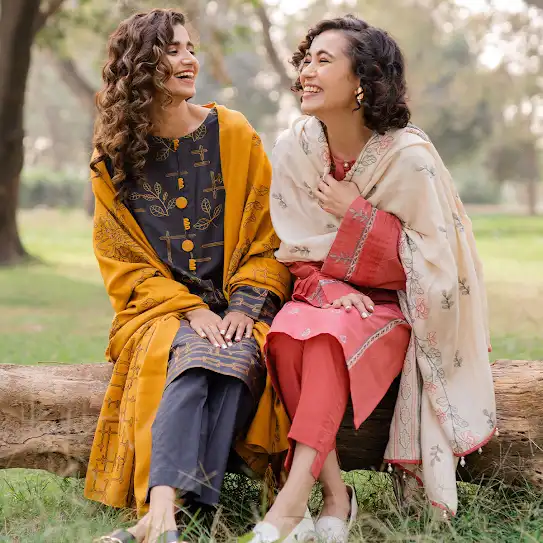 Two women sitting on a horizontal tree trunk