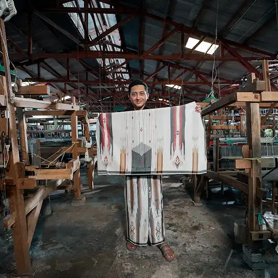 A man showing his woven cloth to the camera