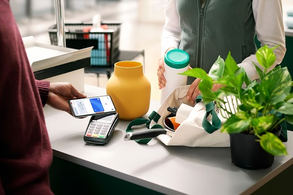 Pessoa realizando uma compra com o telefone celular. O funcion�rio coloca os produtos em uma sacola.