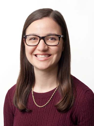 Close up portrait of a smiling woman with long brown hair and glasses