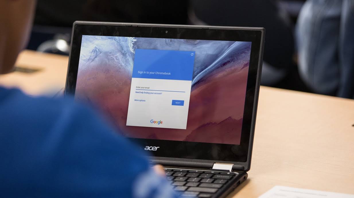 Et besk�ret bilde av en elev som sitter ved en pult og arbeider på en Chromebook der skjermen for Google-pålogging vises.