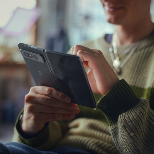 Person sitting and interacting with their foldable Android mobile device.