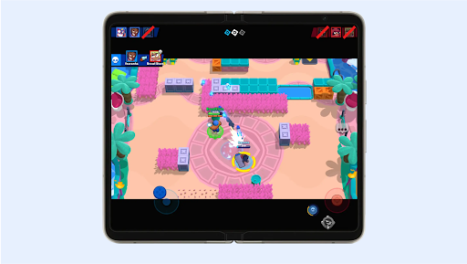 Two characters firing at each other in a colorful arena with pools and trees in Brawl Stars on a foldable phone’s screen.