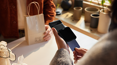 A female shop owner processing a customer’s purchase using a portable credit card machine attached to a Pixel mobile device.