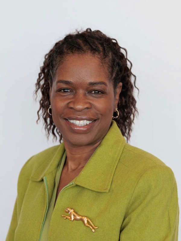 A Black woman wearing a blazer smiles at the camera