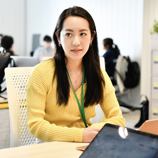 Woman in focus, wearing a yellow top, looking at another person.