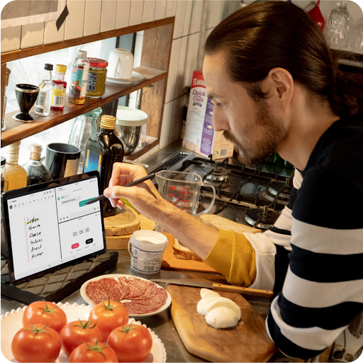 Una persona con un l�piz �ptico en la pantalla de una tablet haciendo varias tareas a la vez: dise�ar, controlar el tiempo con un cron�metro y chatear con alguien.