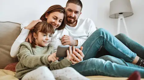 Un couple et sa fille regardant une série discovery+ sur un smartphone