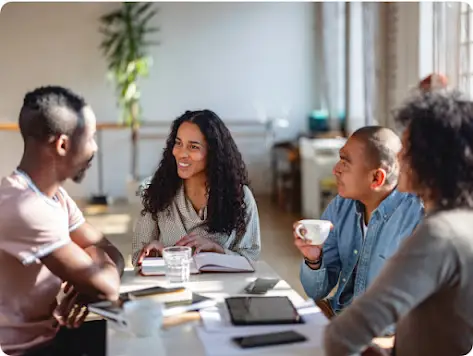 Quatre personnes d’identités de genre et d’origines ethniques différentes ont une conversation autour d’un café.