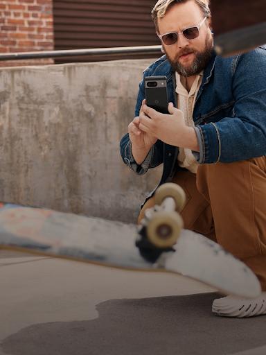 Un usuario de Android agachado mientras graba un v�deo de un skater haciendo un truco.