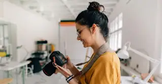 Mulher sorri enquanto usa uma c�mera DSLR.