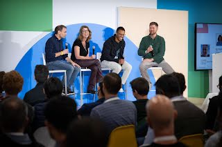 3 men and a woman sitting on chair holding mic on stage