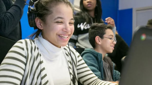 Two students participating in Google’s Code Next program. They are sitting in front of open laptops and smiling.