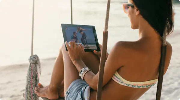 Žena gleda u tablet na plaži