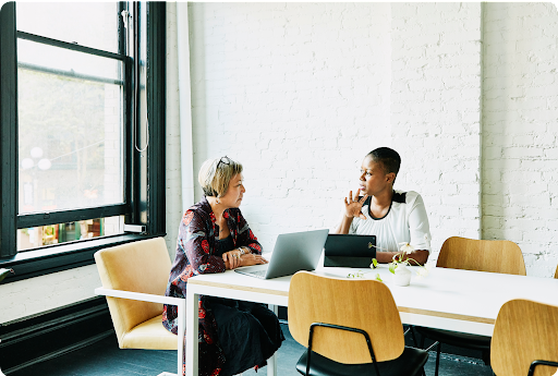 Two people collaborating at a table in a modern meeting room.