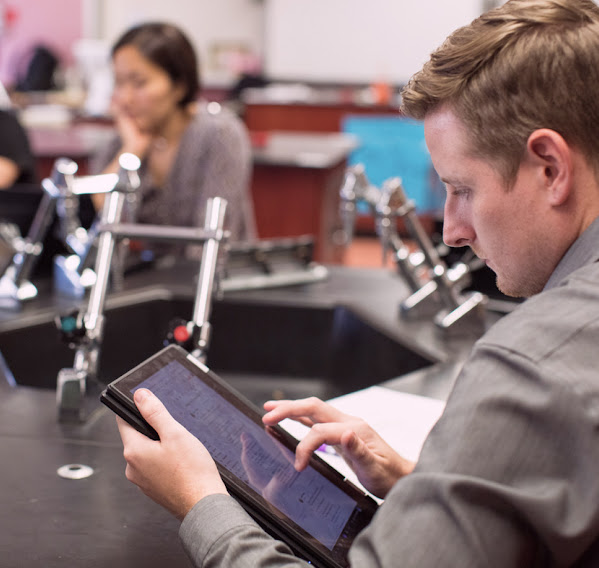 A person works on a tablet in a classroom.