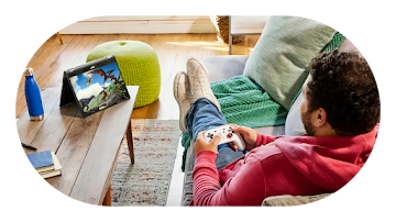 A man sitting on a sofa,  playing video games in a Chromebook device.