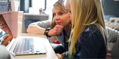 Teacher and girl are in front of a Chromebook, possibly reading about how Google protects the information of Teachers and Students.