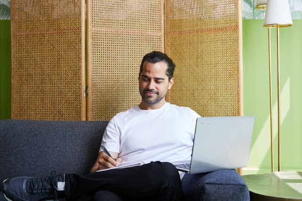 Alberto Villarubia, graduado del programa de Certificados Profesionanles de Google en Dise�o de UX, sentado en un sof� azul mientras trabaja en su computadora port�til.