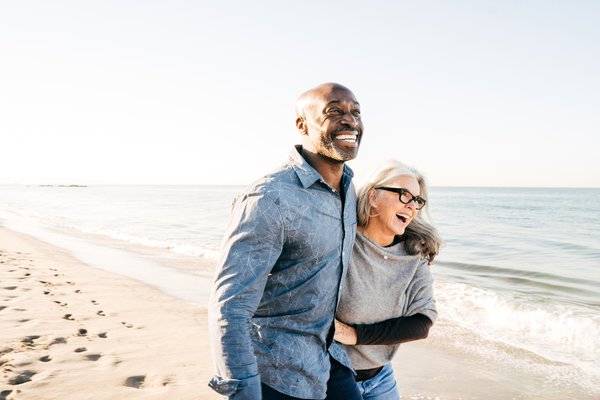 Laughing people arm in arm on the beach.