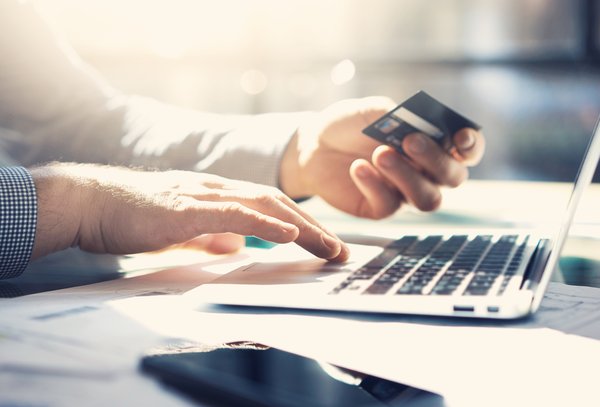 Someone shops on a laptop with credit card in hand.