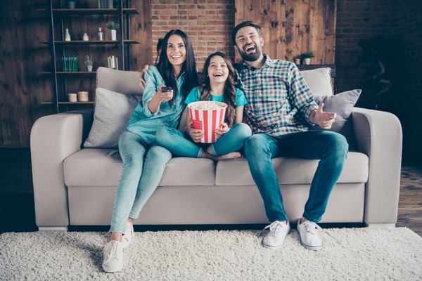 Happy family on couch eating popcorn while watching TV.