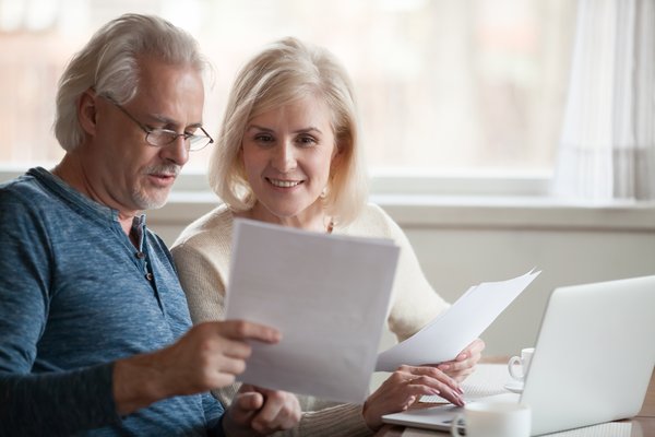 Two people review documents in front of laptop at home.