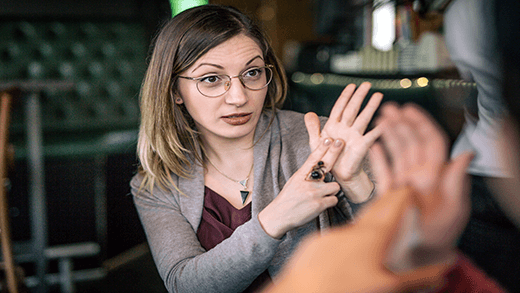 Two women spending time enjoying coffee at the cafe and using sign language as a way of communication.