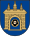 A coat of arms depicting a grey castle with three towers topped by crosses with a human head on the front door all on a blue background