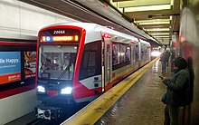 A red modern light rail vehicle at a subway platform