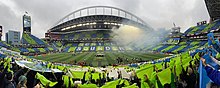 A view from inside the stadium during a tifo display with alternating blue and green cards held up by fans to form a checkerboard pattern in the seats