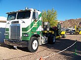 A single rear axle Freightliner cabover hauling an antique engine on a low-boy trailer small enough for a pickup truck. What a sight for sore eyes.