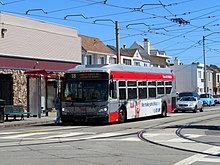 A bus on a street with overhead wires