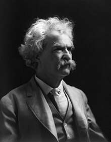 Photograph of man with a shock of white hair and a white mustache, wearing a three-piece suit. He is looking off to the right.