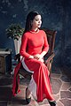 A woman wearing red Áo dài sitting on a chair, December 2016