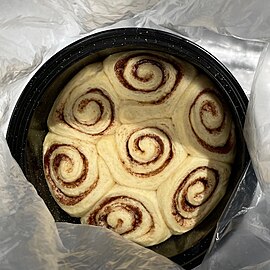 The rolls have expanded even more, to fill the entire pan from edge to edge with no gaps. The dough looks dry but is pale and soft