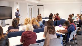 Lektor stands in front of university students in a seminar