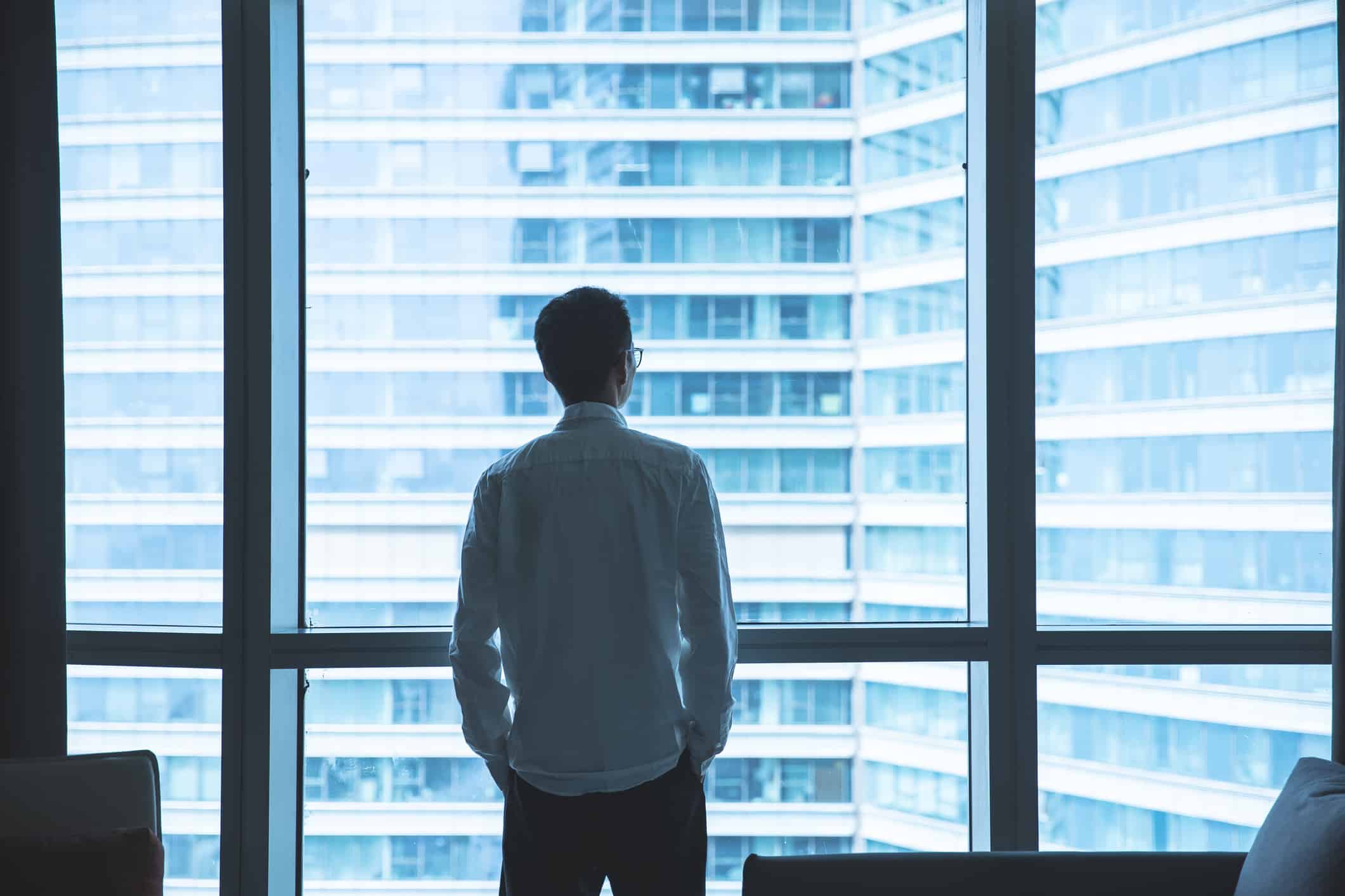 a person looks out a window into a cityscape