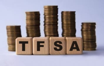 TFSA (Tax free savings account) acronym on wooden cubes on the background of stacks of coins