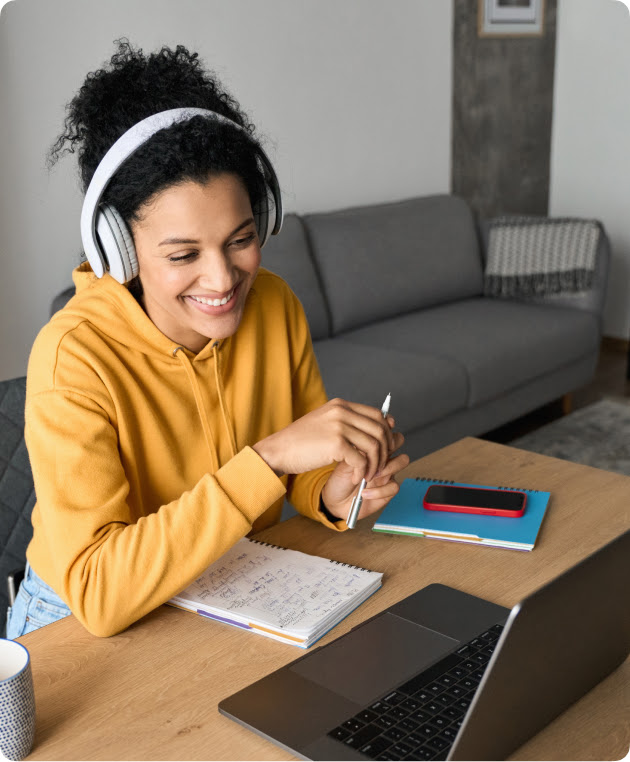 Woman working on laptop while wearing headphones