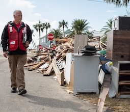 red cross volunteer walks past destruction after hurricane helene