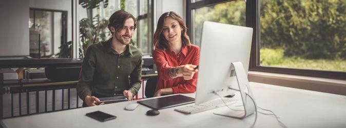 Zwei junge Menschen sitzen vor einem Computer 