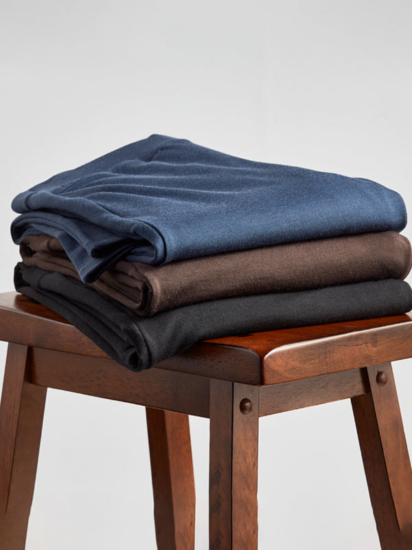 Stack of new Ellie pants on chair in deep navy, french roast, and black