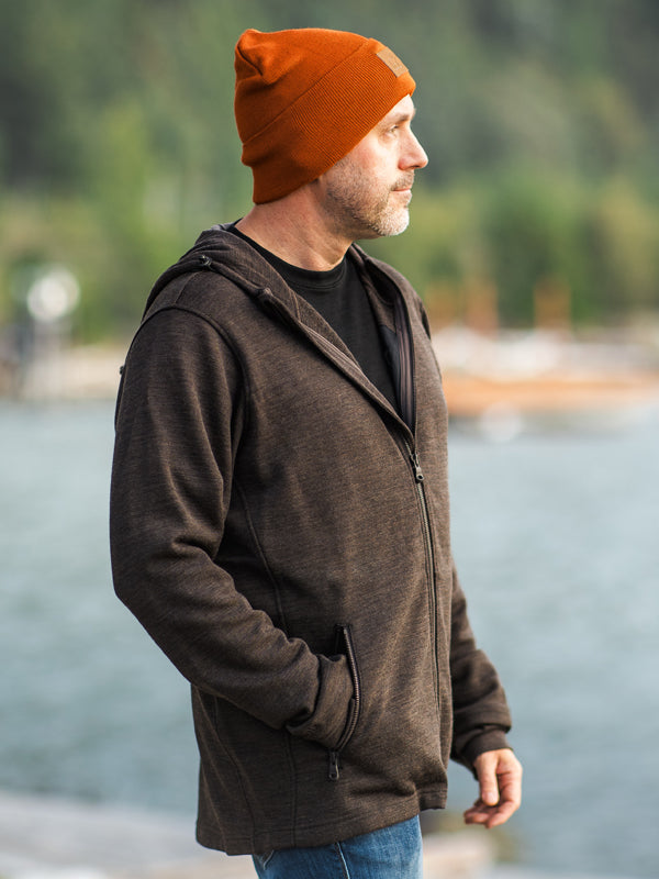 Man wearing popular Grizzly sweatshirt by a lake while also wearing bright orange baylor beanie