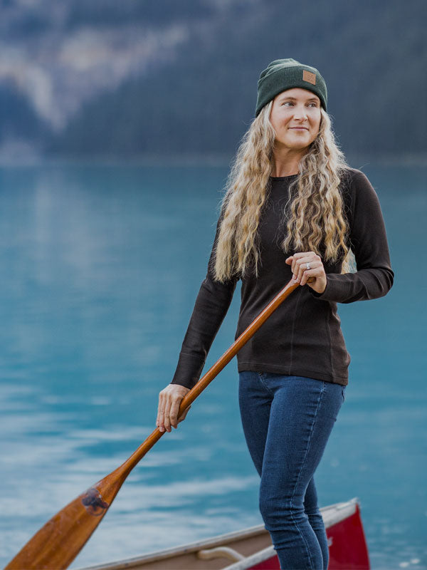 Woman wearing Hannah base layer top and Baylor beanie while standing on boat in middle of lake mobile size