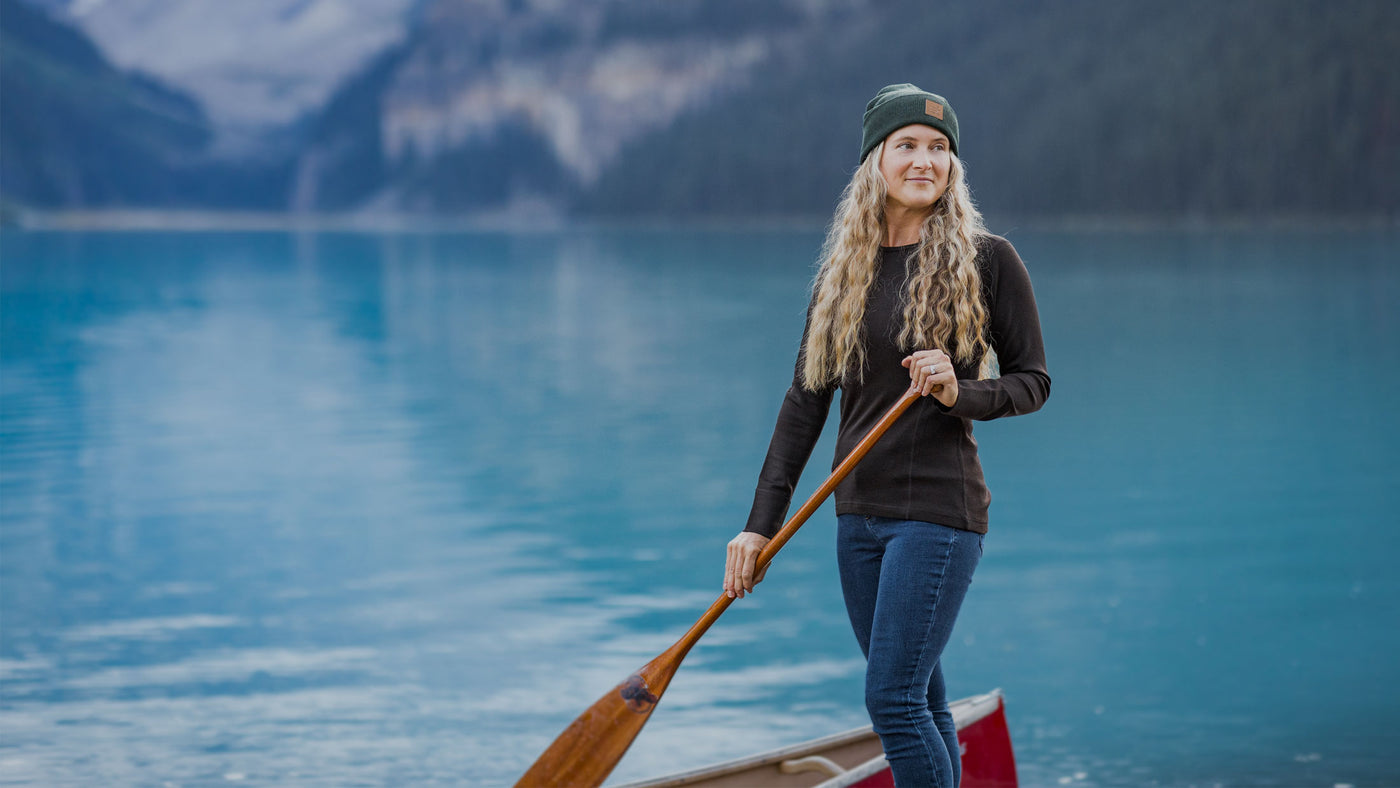 Woman wearing Hannah base layer top and Baylor beanie while standing on boat in middle of lake