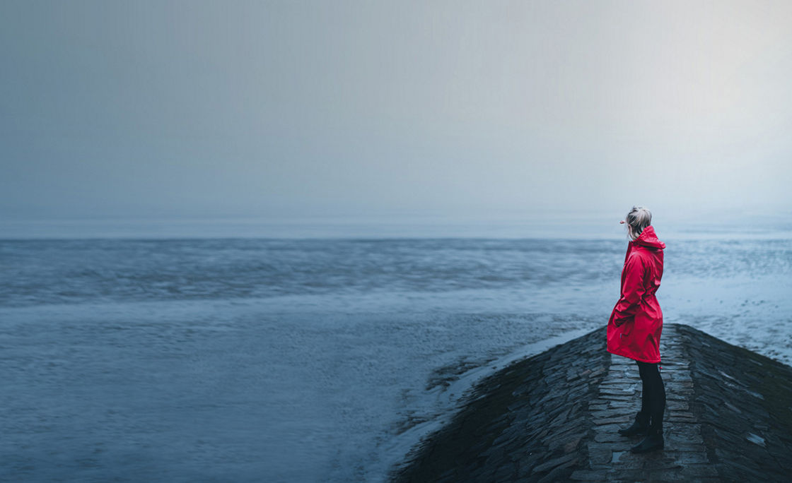 girl in red jacket looking in the distance on the foggy beach