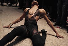 Photographie d'un danseur noir en train de voguer. Il porte une tenue noir en dentelle.