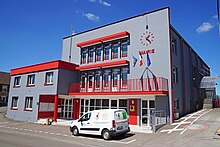 Bâtiment cubique gris et rouge à trois niveau.